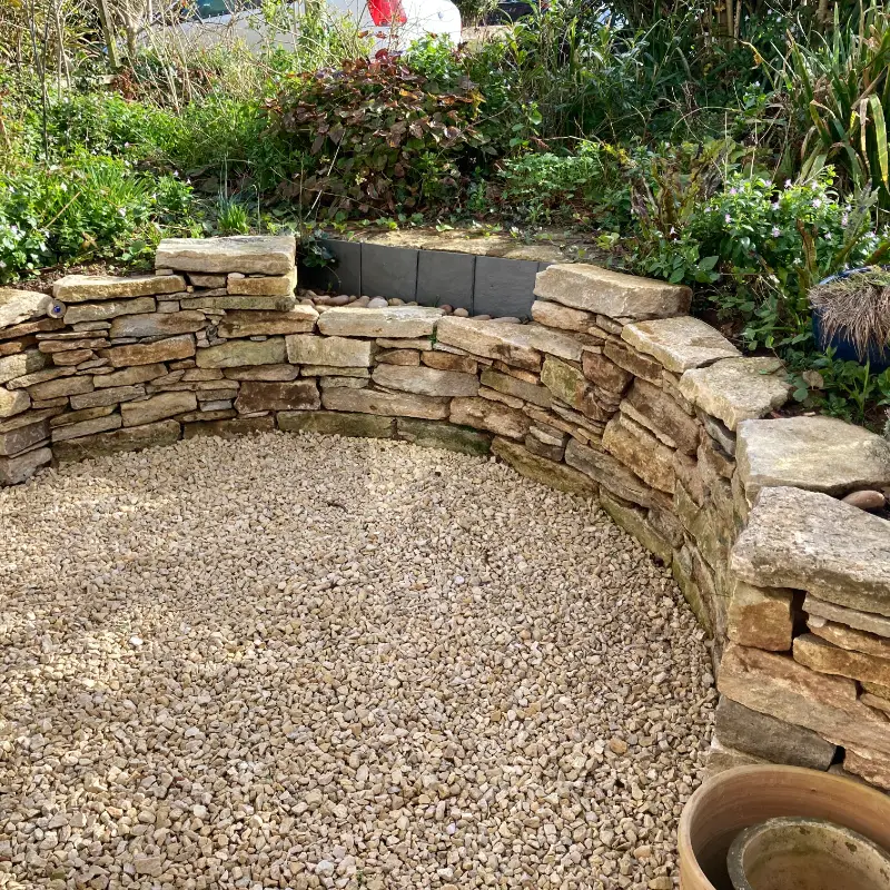 Semi-circular, dry-stone retaining wall with seating area.